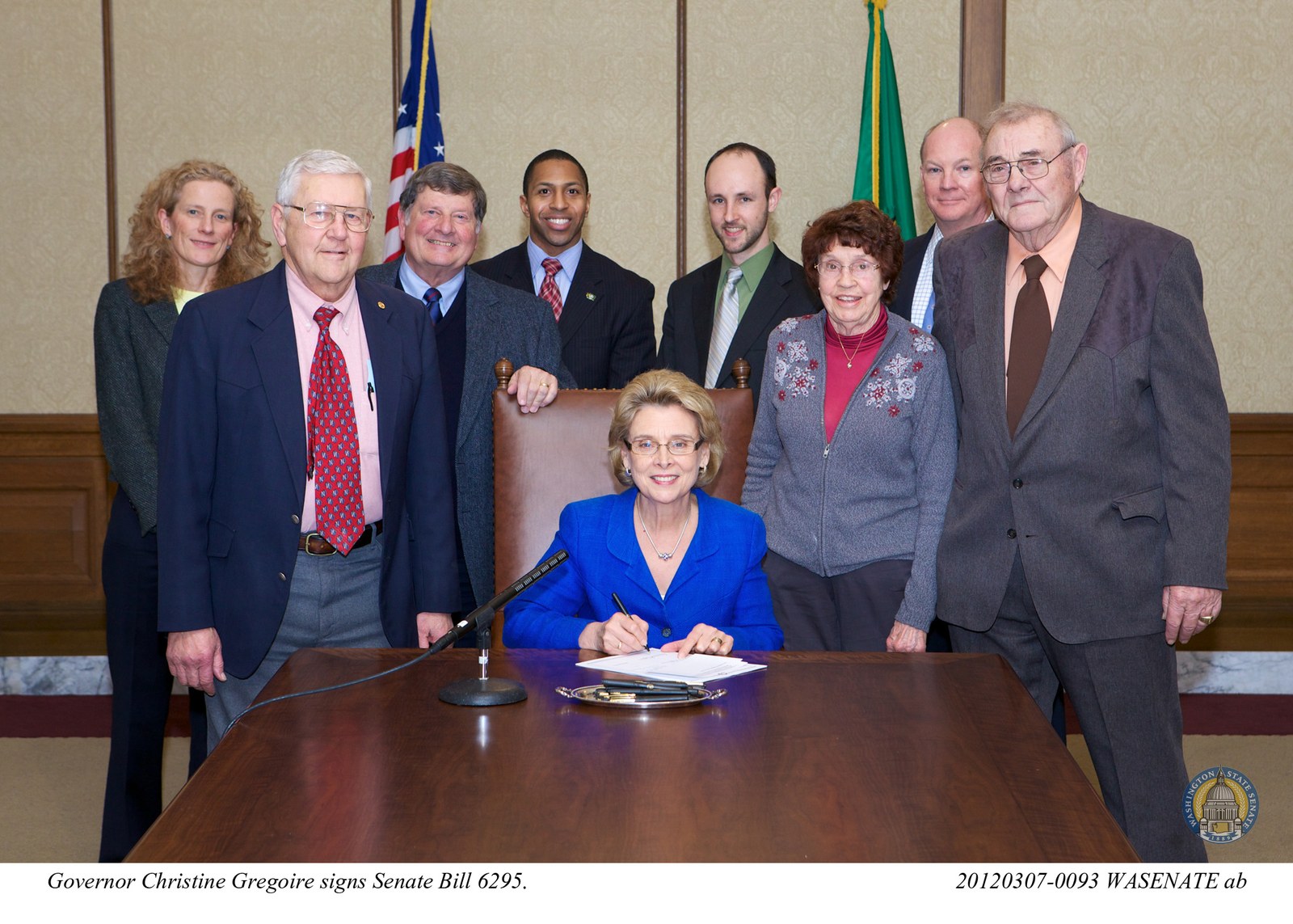 Governor Christine Gregoire signs Washington Senate Bill 6295 on March 7, 2012, regulating 1031 exchange facilitators. Jeff Helsdon of Olympic Exchange Accommodators stands in the back row wearing a blue tie.